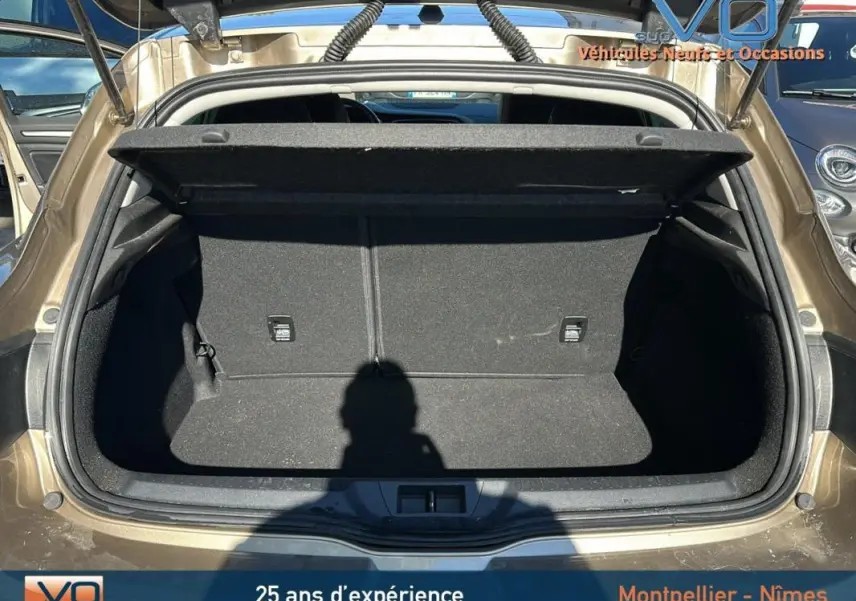 Coffre ouvert vu de l'arrière d'une Renault Mégane IV beige, montrant l'espace de chargement vide et propre.