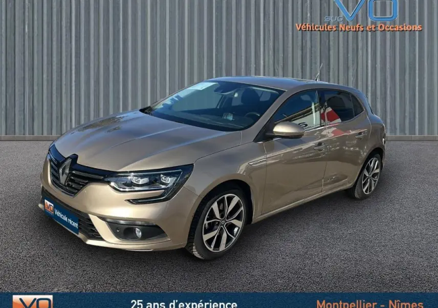 Renault Mégane IV beige vue 3/4 avant droit, avec jantes alliage et phares LED allumés sur fond urbain.