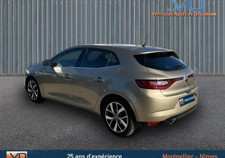 Vue 3/4 arrière droite d'une Renault Mégane IV beige, avec jantes alliage et feux arrière LED distinctifs.