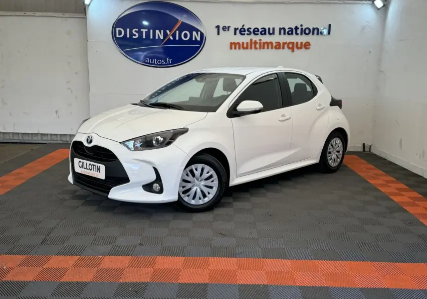 Toyota Yaris hybride blanche vue 3/4 avant droit, avec calandre noire et feux ellipsoïdaux LED.