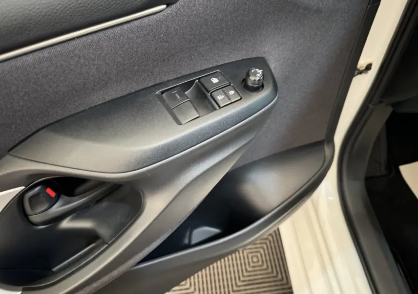 Gros plan sur la porte avant gauche blanche d'une Toyota Yaris hybride, montrant les commandes de vitres et rétroviseurs.