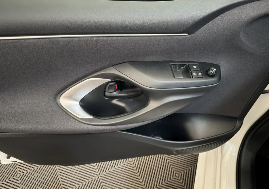Poignée intérieure et commandes de porte côté gauche de la Toyota Yaris hybride blanche 2022, avec bouton de réglage des rétroviseurs.