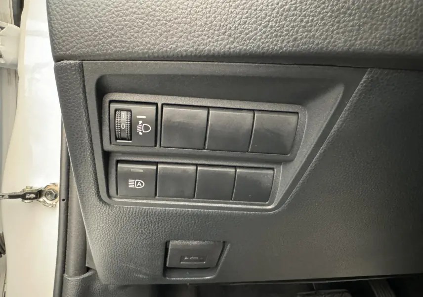 Panneau de commandes côté conducteur de la Toyota Yaris blanche 2022 avec réglage phares et assistant feux automatiques.