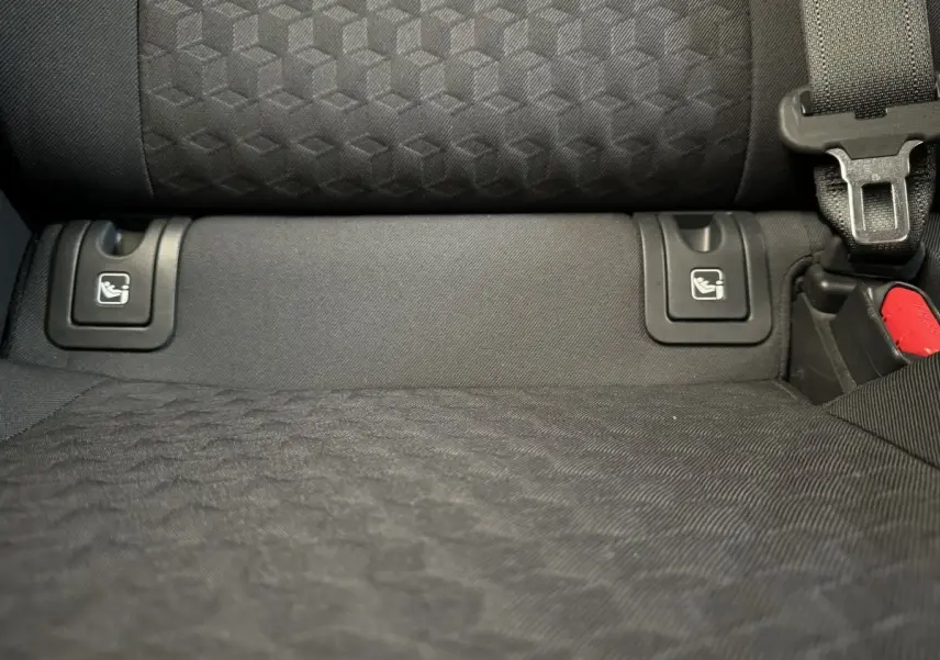 Gros plan sur la banquette arrière noire de la Toyota Yaris Hybride 116h, montrant les fixations Isofix et la ceinture de sécurité.