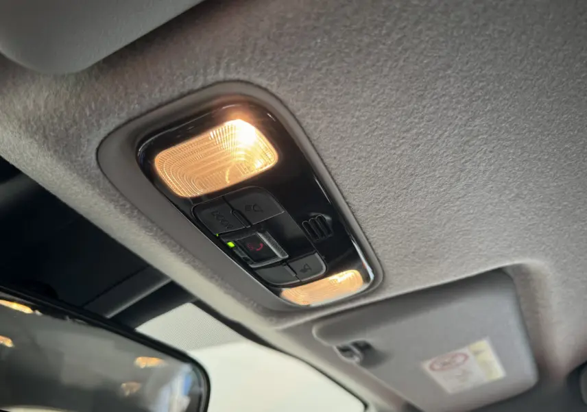 Plafonnier intérieur allumé avec commandes d’éclairage et bouton SOS dans une Toyota Yaris blanche hybride 2022.