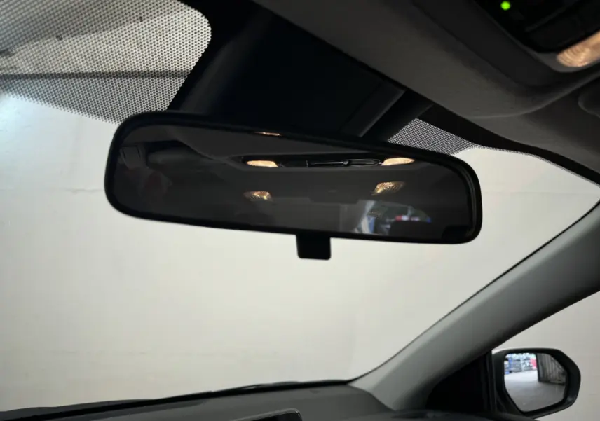 Vue intérieure centrée sur le rétroviseur intérieur de la Toyota Yaris hybride blanche, avec partie du tableau de bord visible.