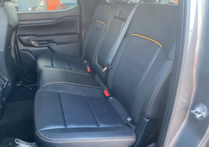 Vue intérieure arrière côté droit du Ford Ranger 205 Wildtrak X, sièges cuir noirs avec surpiqûres orange.