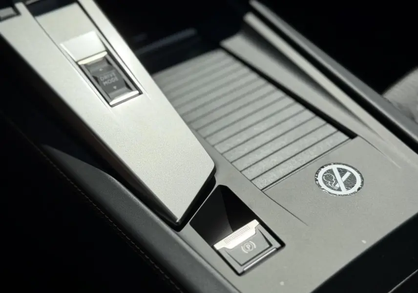 Gros plan sur la console centrale noire avec bouton Drive Mode et frein de parking électrique du Peugeot 308 SW 2024.