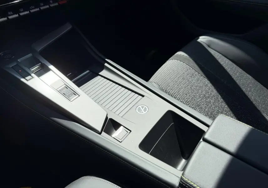 Gros plan sur la console centrale grise et siège tissu noir de la Peugeot 308 SW 2024, intérieur moderne et épuré.
