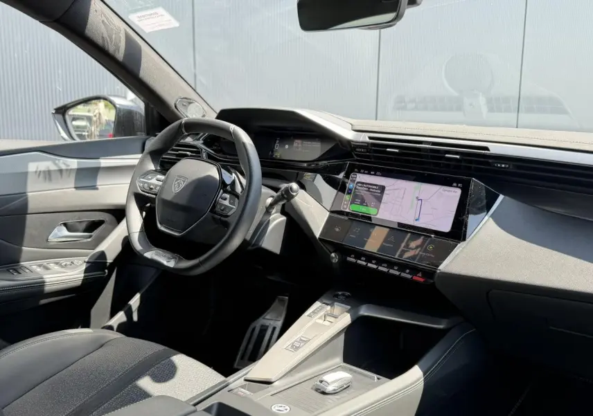 Vue intérieure côté conducteur du Peugeot 308 SW 2024, mettant en valeur le tableau de bord numérique et l’écran tactile central.