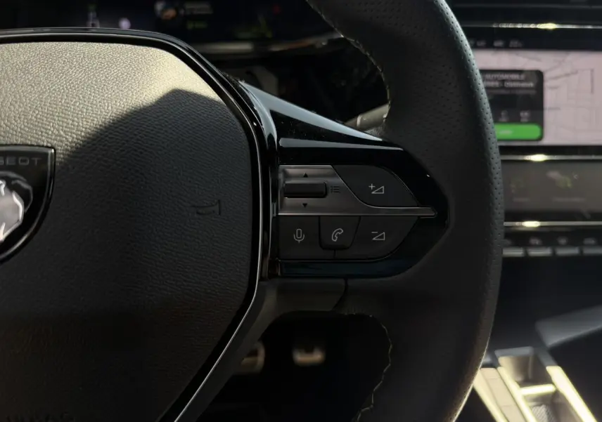 Gros plan sur les commandes à droite du volant cuir perforé de la Peugeot 308 SW 2024, intérieur noir.