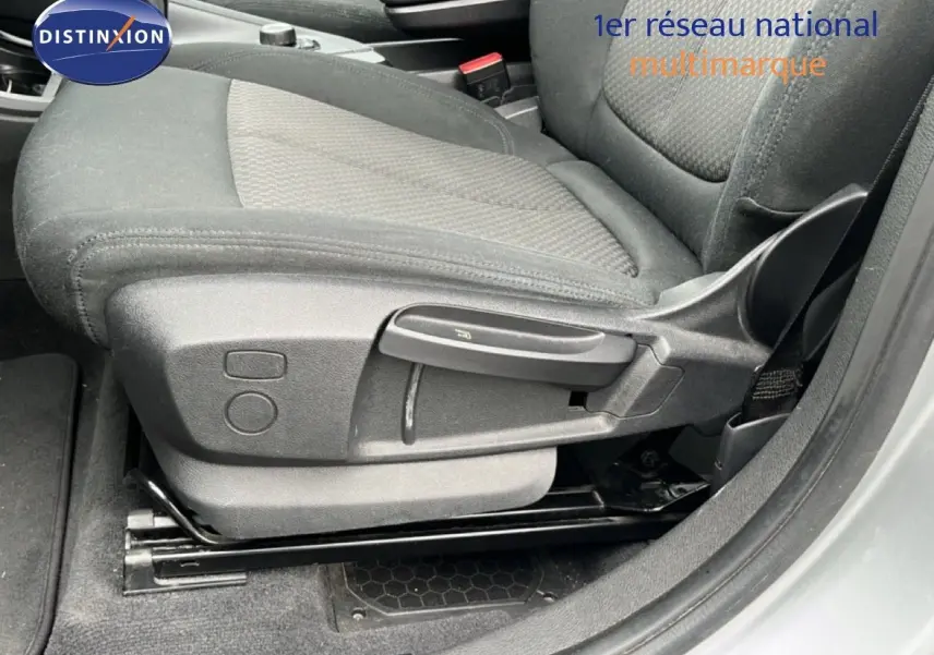 Gros plan sur le siège avant droit en tissu gris noir d’un BMW X1 gris argent métal, avec réglages manuels visibles.