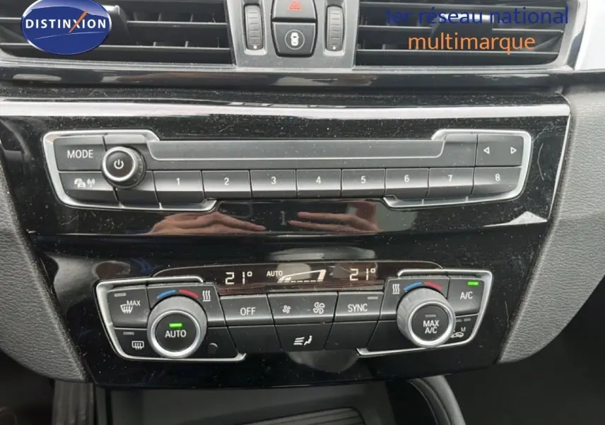 Vue rapprochée de la console centrale noire du BMW X1 18i 2018, avec commandes climatisation et multimédia.