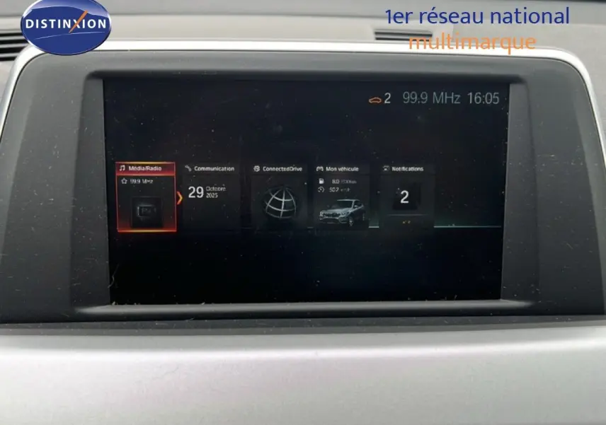 Écran multimédia du tableau de bord du BMW X1 18i gris argent, affichant radio et informations véhicule.