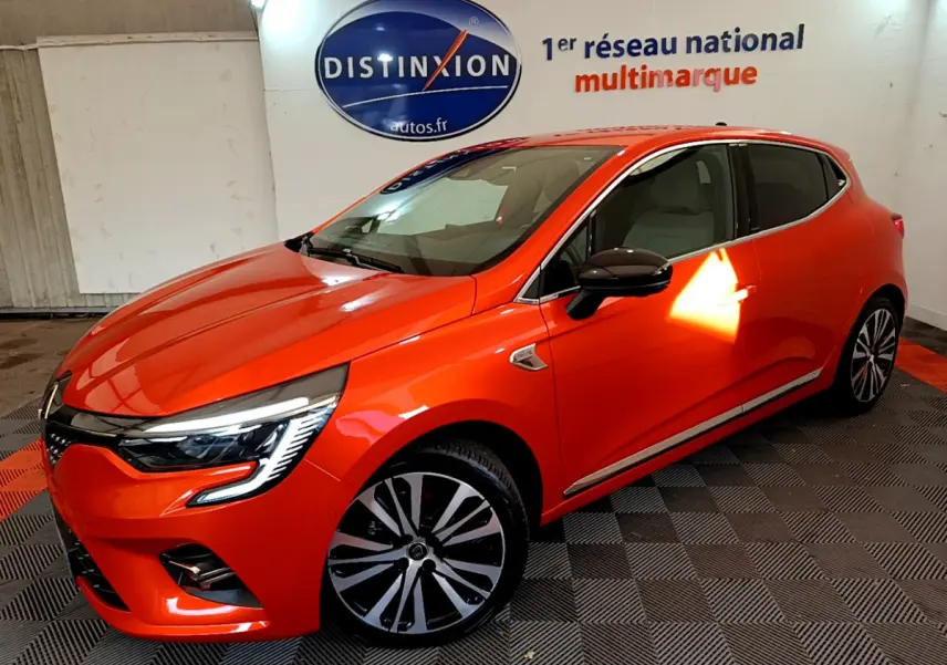 Renault Clio Initiale Paris orange vue 3/4 avant droit en intérieur avec jantes alliage et phares LED distinctifs