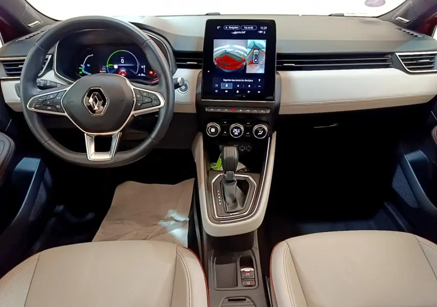 Vue intérieure avant du tableau de bord beige et noir de la Renault Clio Initiale Paris E-TECH 140 avec écran tactile central et volant cuir.