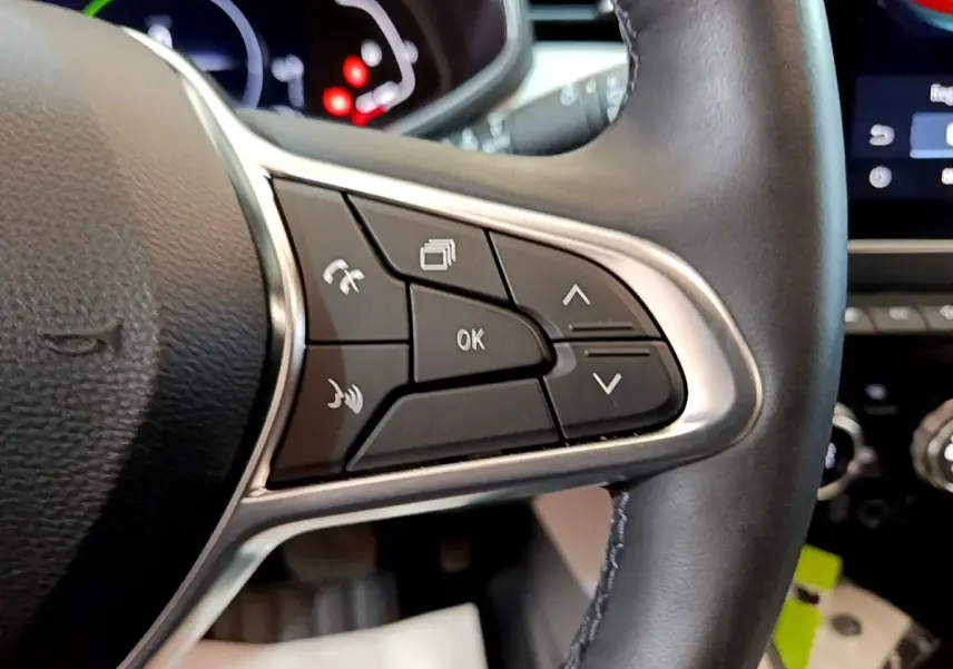 Gros plan sur les commandes au volant droit en cuir noir de la Renault Clio Initiale Paris E-TECH 140 orange 2021.