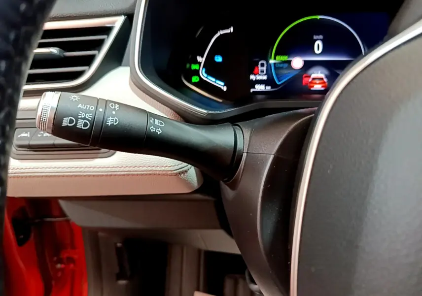 Gros plan sur le commodo gauche et le tableau de bord numérique d'une Renault Clio Initiale Paris orange 2021.