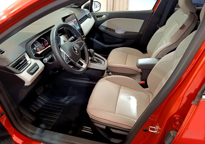Intérieur avant droit d'une Renault Clio Initiale Paris orange 2021, sièges cuir beige et tableau de bord moderne.