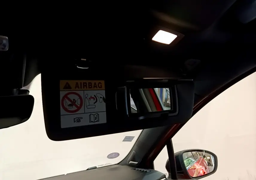 Détail du pare-soleil côté conducteur avec miroir et avertissement airbag dans Renault Clio Initiale Paris orange, vue intérieure avant.
