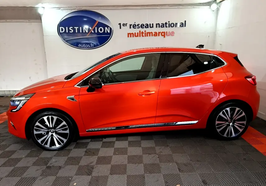 Profil côté gauche d'une Renault Clio Initiale Paris orange 2021 avec jantes alliage et rétroviseurs noirs brillants.
