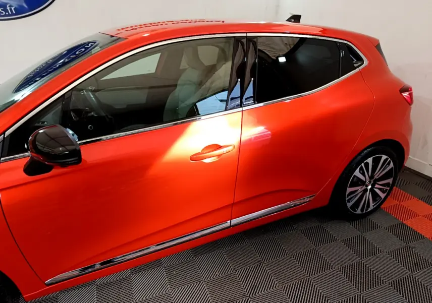 Profil côté gauche de la Renault Clio Initiale Paris orange 2021 avec jantes alliage et rétroviseur noir brillant.