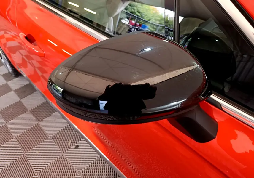 Rétroviseur noir en gros plan côté gauche sur Renault Clio Initiale Paris E-TECH 140 orange vue latérale