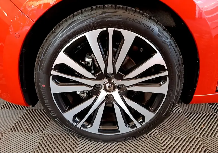 Gros plan sur la roue avant gauche de la Renault Clio Initiale Paris orange, jante alliage bicolore au design moderne.