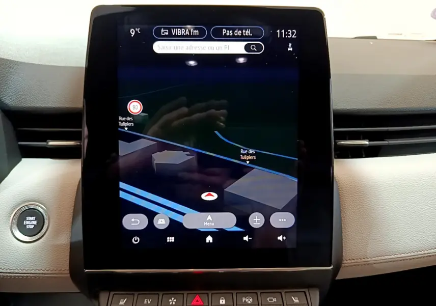 Écran tactile central affichant la navigation dans l'habitacle beige d'une Renault Clio Initiale Paris orange, bouton démarrage visible.