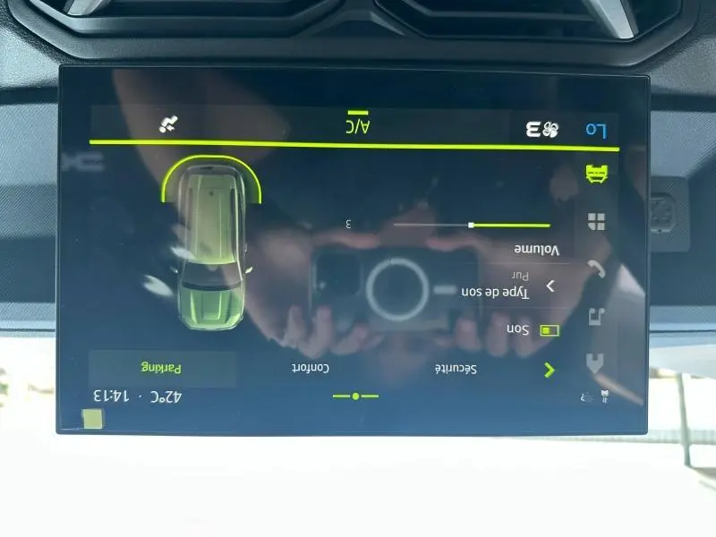 Écran tactile intérieur du Dacia Duster blanc montrant les réglages audio et de sécurité, vue de face.
