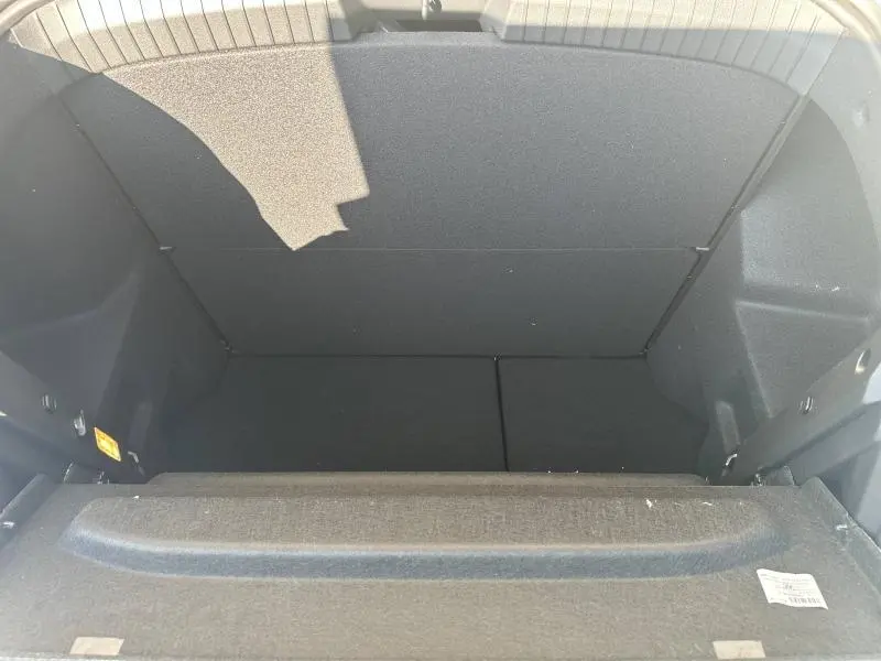 Coffre ouvert vu de dessus du Dacia Duster blanc 2025, montrant un espace de rangement noir et une tablette cache-bagages.