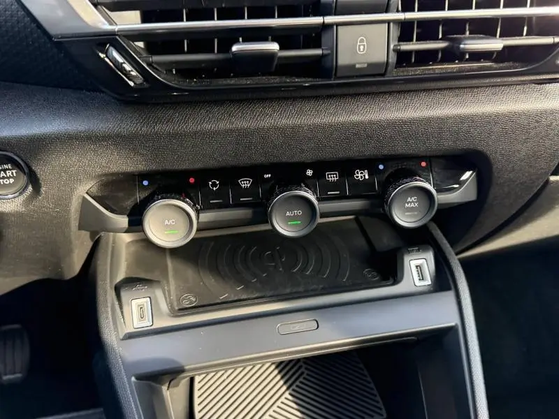 Vue rapprochée du tableau de bord du Citroën C4 2024 gris, montrant les commandes de climatisation et la zone de recharge sans fil.
