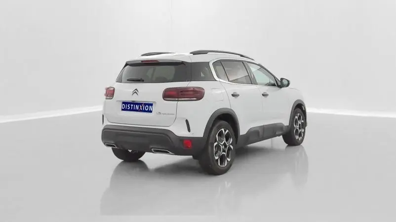 Vue 3/4 arrière droite d'un Citroën C5 Aircross hybride blanc avec toit noir et jantes distinctives.