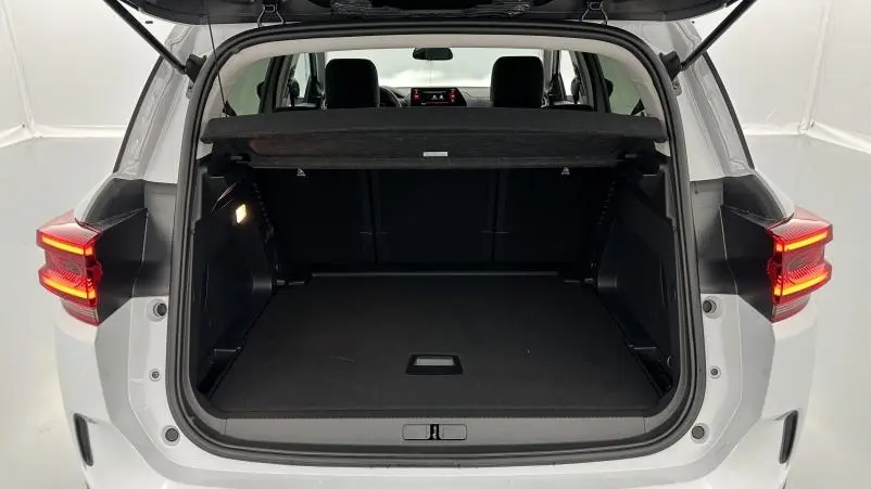 Vue arrière du coffre ouvert d'un Citroën C5 Aircross hybride blanc, avec feux arrière allumés et intérieur noir visible.
