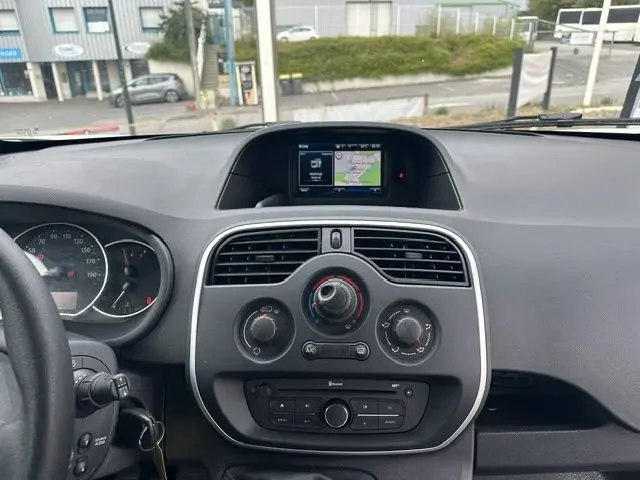 Tableau de bord du Renault Kangoo 2020 en vue frontale, avec écran GPS intégré et commandes de climatisation visibles.