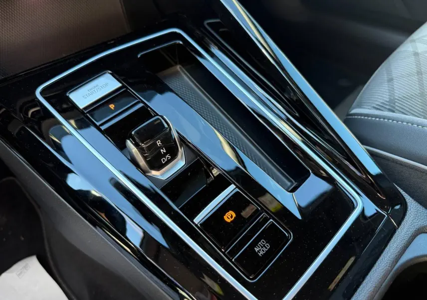 Vue en plongée sur la console centrale noire brillante avec levier de vitesses et bouton start/stop de la Volkswagen Golf 2024.