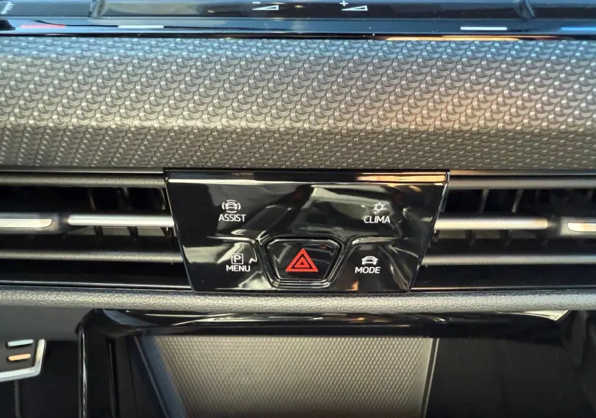 Détail du tableau de bord noir avec commandes d'assistance, climatisation et mode sur Volkswagen Golf 2024.