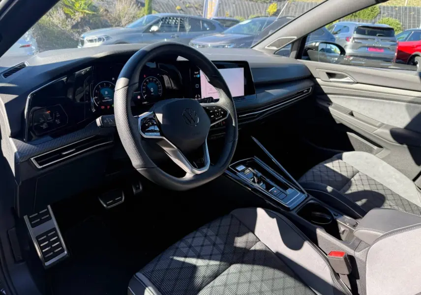 Vue intérieure côté conducteur de la Volkswagen Golf 2024, volant cuir multifonction et sièges sport en tissu gris anthracite.