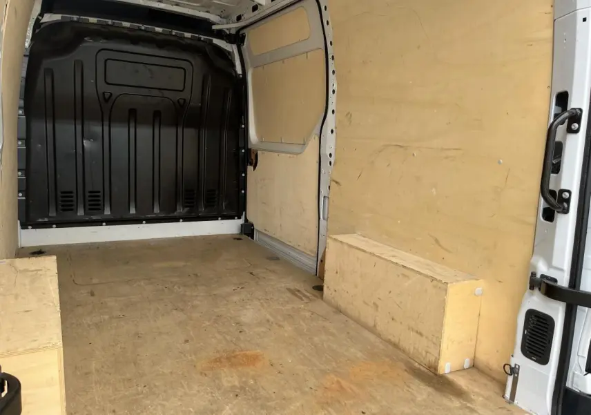 Intérieur du coffre du Renault Master blanc, vue depuis l'arrière droit, avec plancher et parois en bois clair.