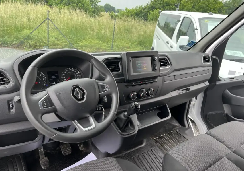 Intérieur du Renault Master 2022 vu côté conducteur, tableau de bord noir avec volant et banquette tissu gris.