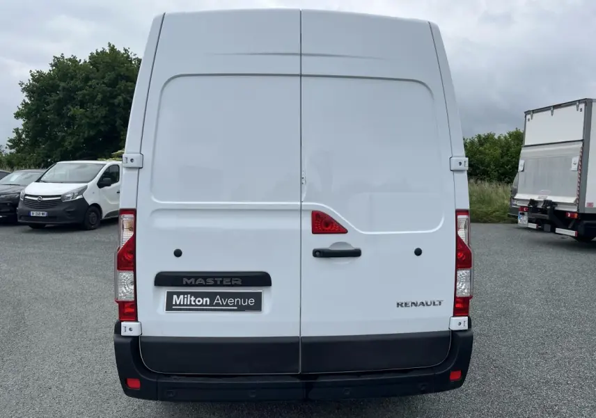 Vue arrière d'un Renault Master blanc avec portes arrière tôlées et logo visible sur un parking.