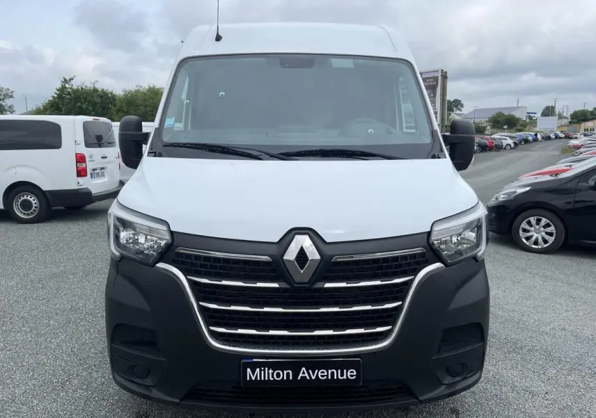 Vue de face d'un Renault Master blanc avec calandre noire et logo Renault bien visible sur un parking.