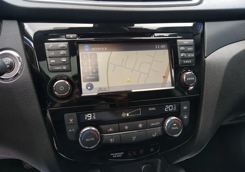 Vue rapprochée du tableau de bord noir du Nissan Qashqai 2018 avec écran GPS et commandes de climatisation digitales.