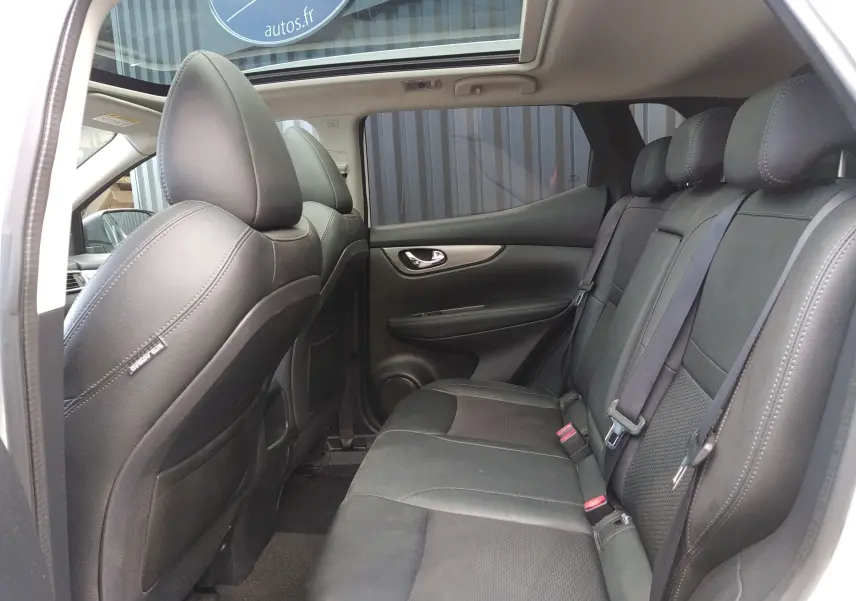 Vue intérieure côté droit montrant les sièges arrière en cuir noir du Nissan Qashqai blanc 2018 avec toit panoramique.