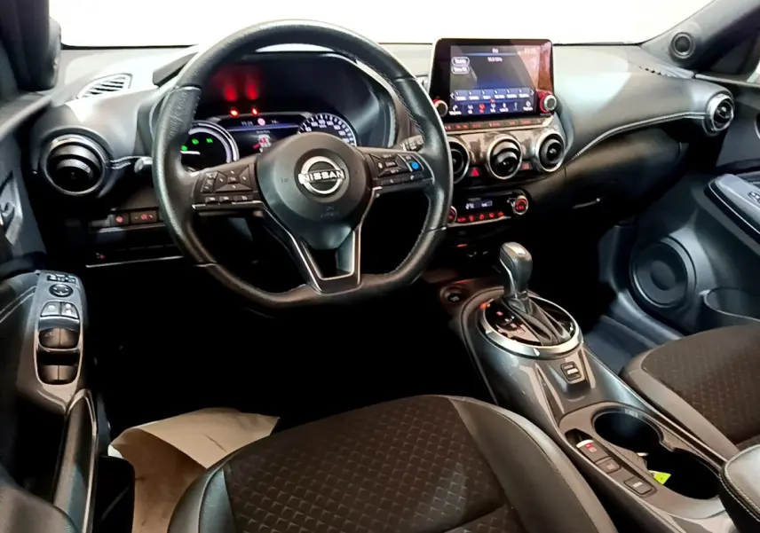 Intérieur du Nissan Juke Hybrid 143 Business+ 2023, vue cockpit côté conducteur, tableau de bord et console centrale noirs.