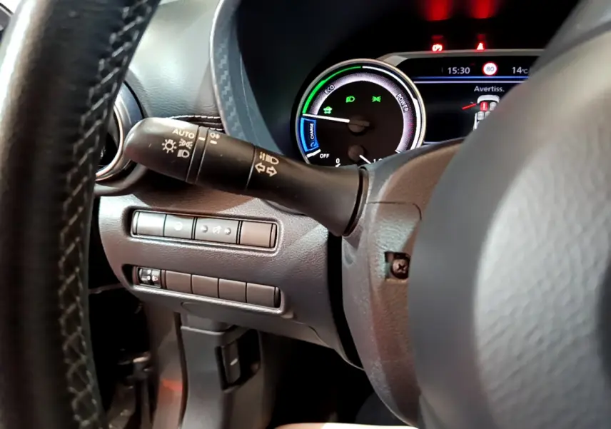 Gros plan sur le combiné d'instruments et la commande des phares à gauche du volant du Nissan Juke Hybrid gris foncé 2023.