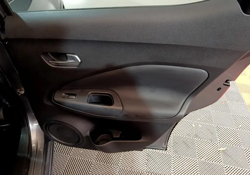 Vue rapprochée de la porte arrière droite gris foncé du Nissan Juke Hybrid 143 Business+ avec poignée et haut-parleur intégrés.