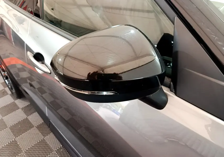 Rétroviseur noir brillant côté gauche du Nissan Juke Hybrid gris foncé 2023 avec clignotant intégré visible.