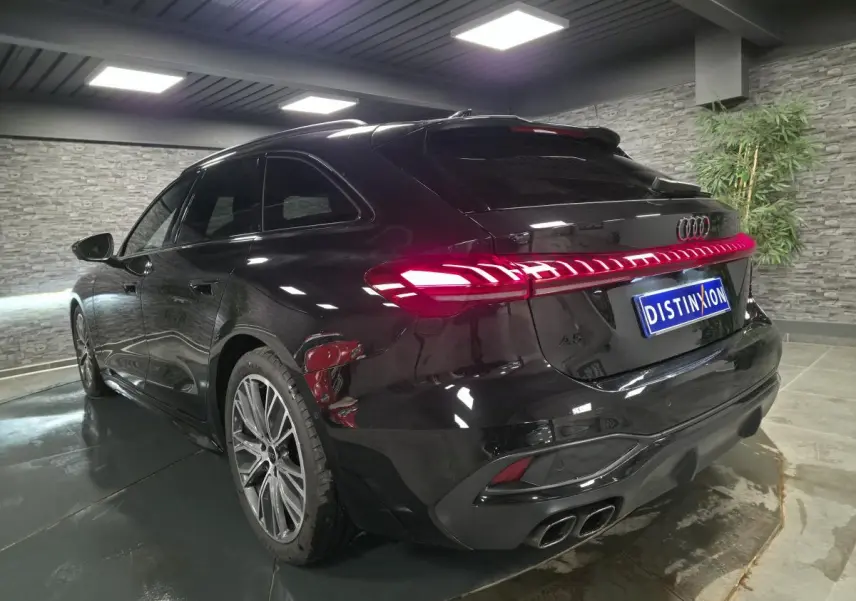 Audi A5 Avant noire vue en 3/4 arrière droit, avec feux arrière LED allumés et jantes 19 pouces style V.