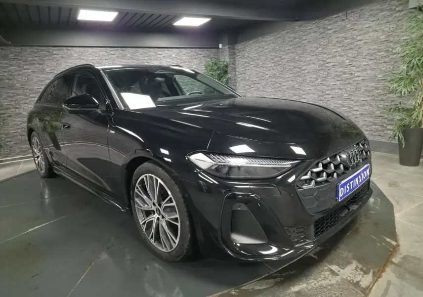 Audi A5 Avant noir vue 3/4 avant droit, avec calandre S line et jantes 19 pouces en V gris graphite.